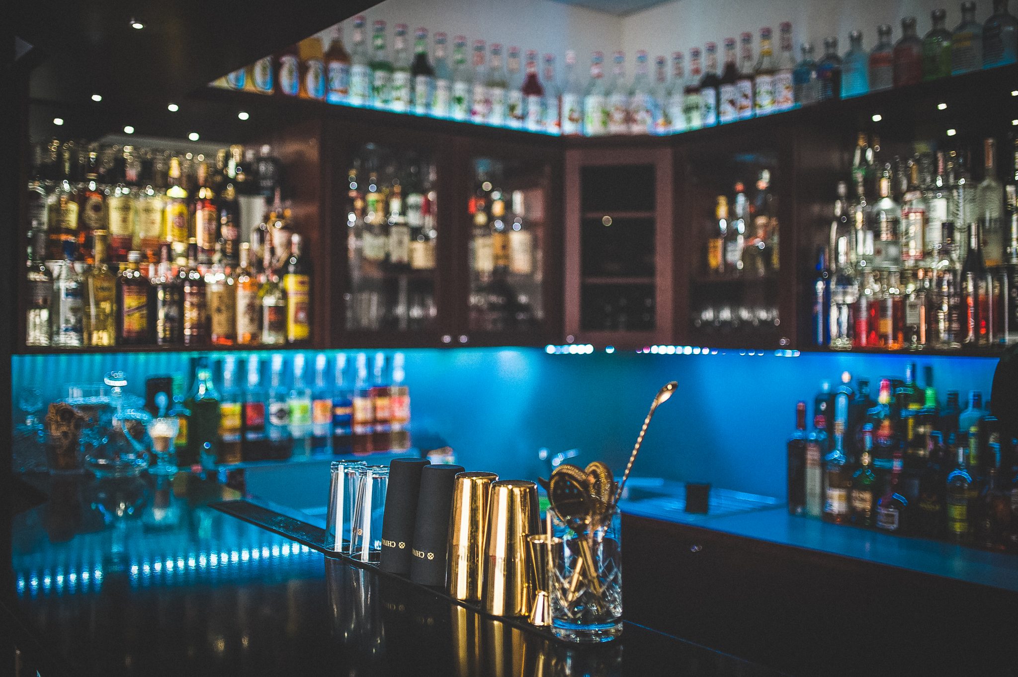 Bar Dream Cocktail s barmanským náčiním a osvetlenými policami fliaš